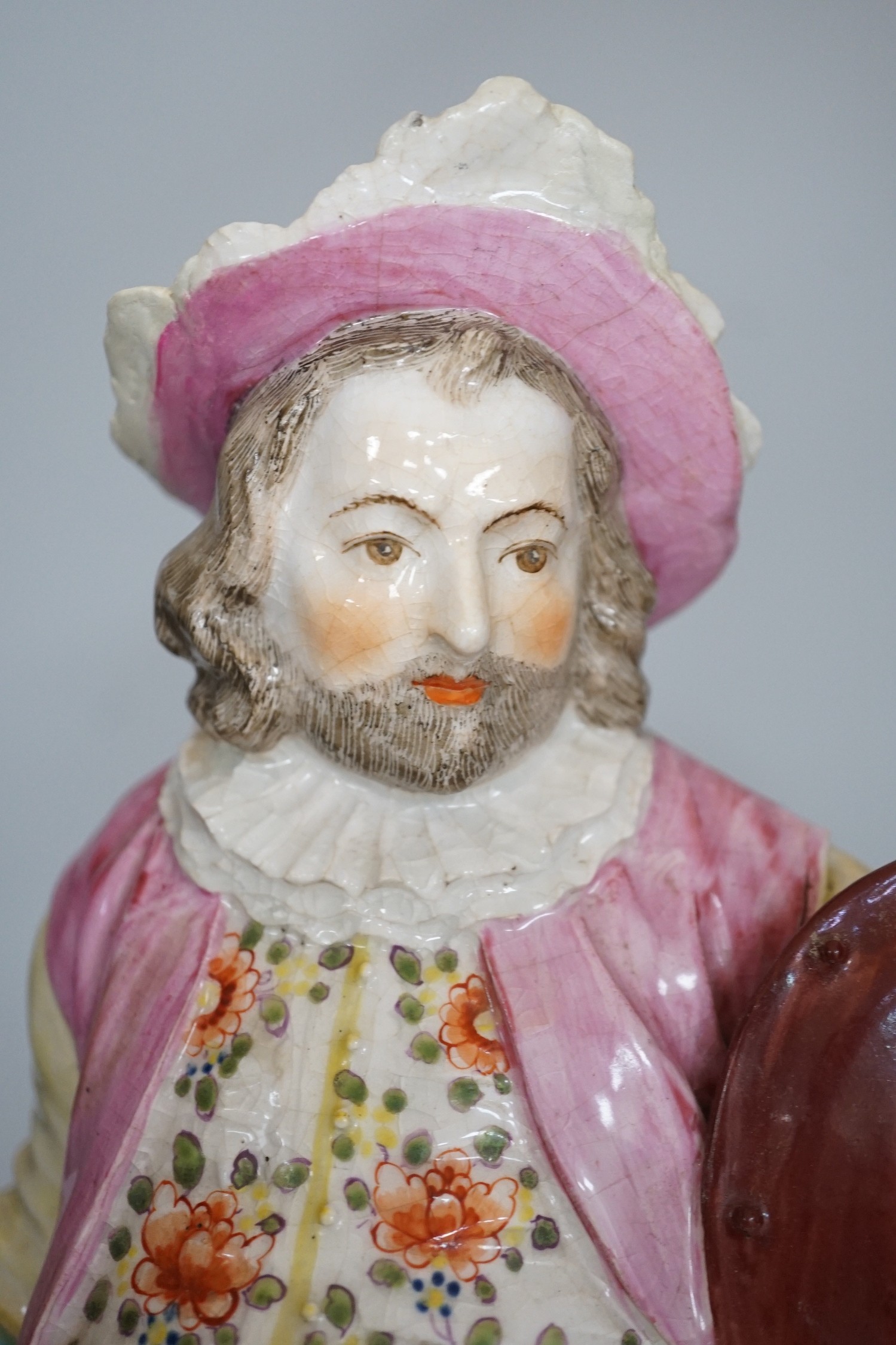 A large Derby figure of Falstaff standing, holding a sword and shield, patch marks, original brass sword, is now a modelled replacement, 39cms high